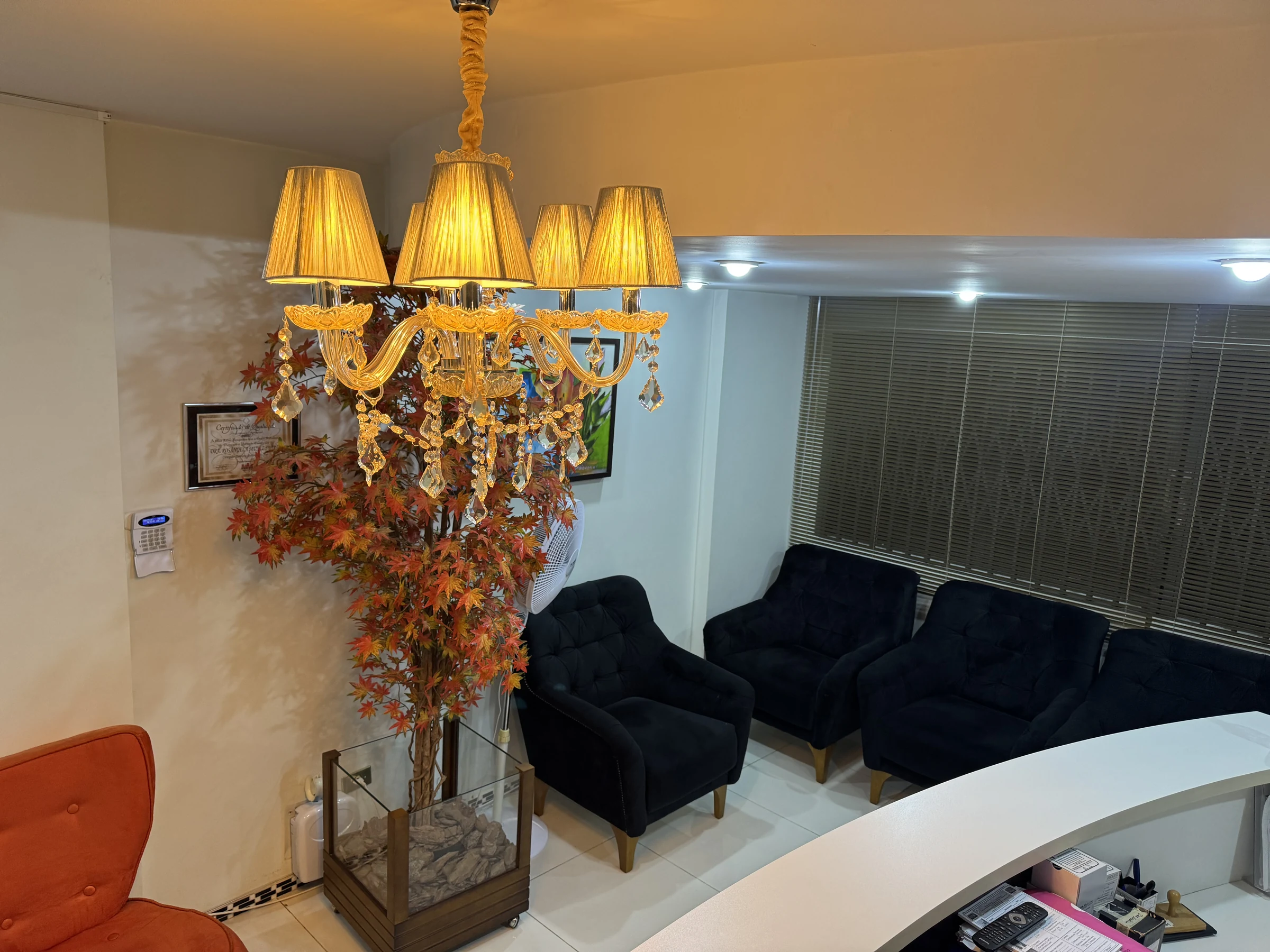 Sala de espera do consultório vista do alto, com lustre, poltronas e recepção