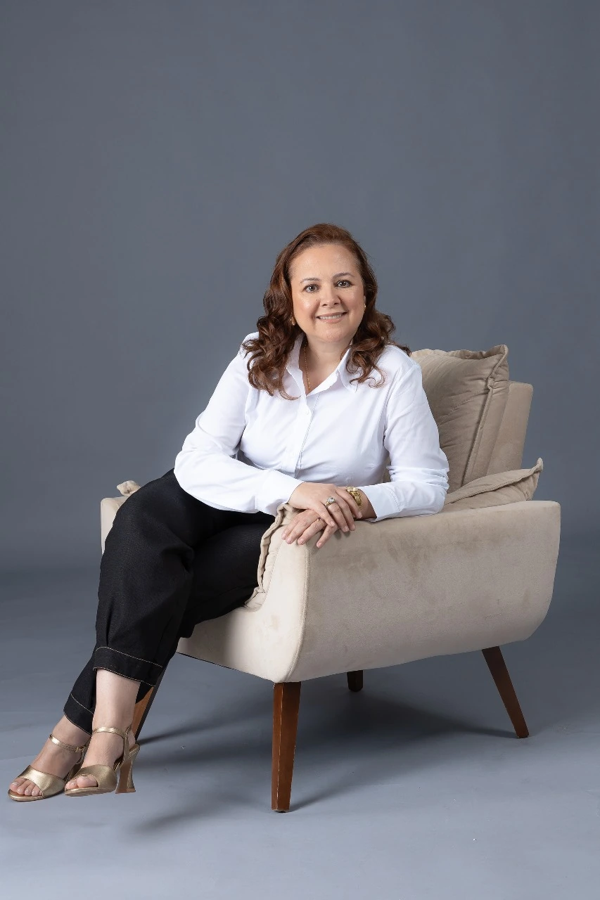 Dra. Rosângela Muniz Soares, cirurgiã-dentista, de camisa branca, sentada em uma poltrona clara